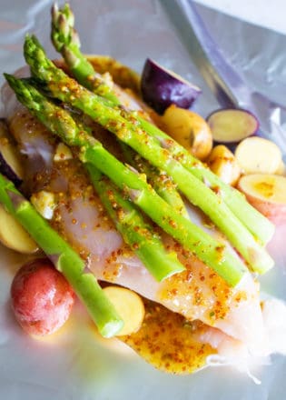 asparagus with chicken, honey mustard, chicken and potatoes on top of foil