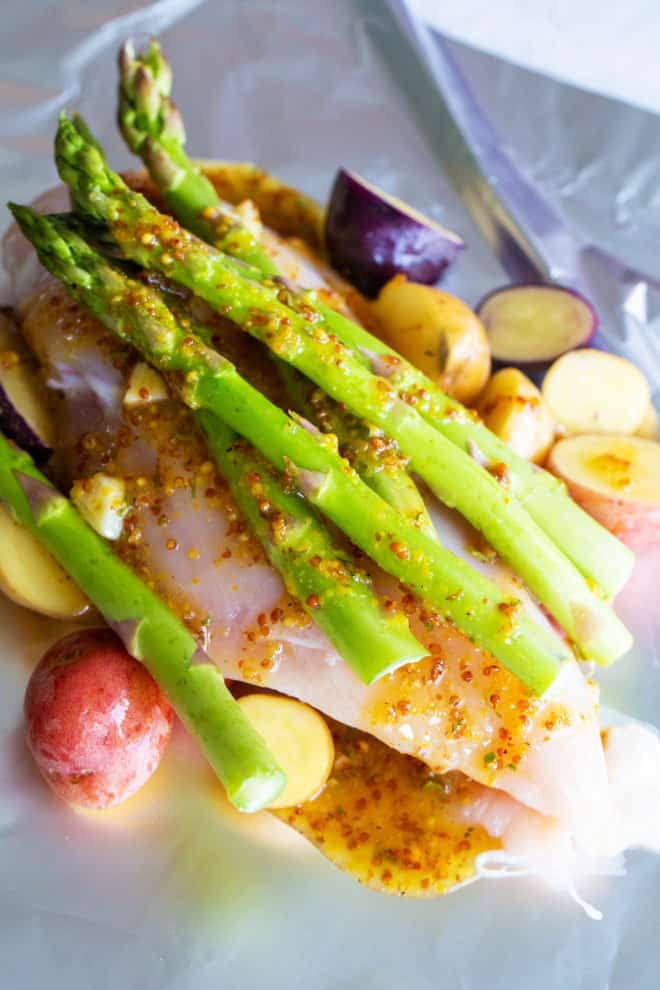 asparagus with chicken, honey mustard, chicken and potatoes on top of foil