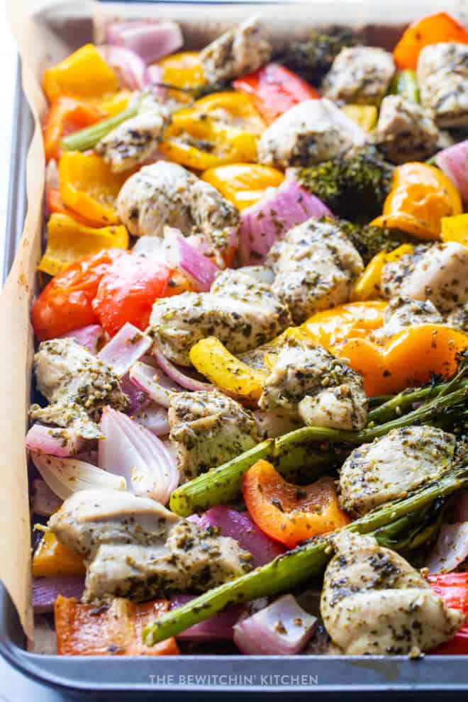 over head view of roasted veggies and pesto chicken on a sheet pan