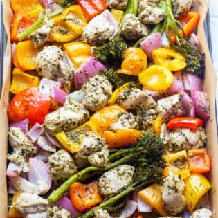 Roasted chicken and vegetables out of the oven on a sheet pan lined with parchment paper