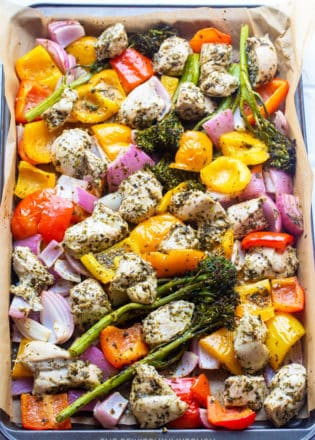 Roasted chicken and vegetables out of the oven on a sheet pan lined with parchment paper