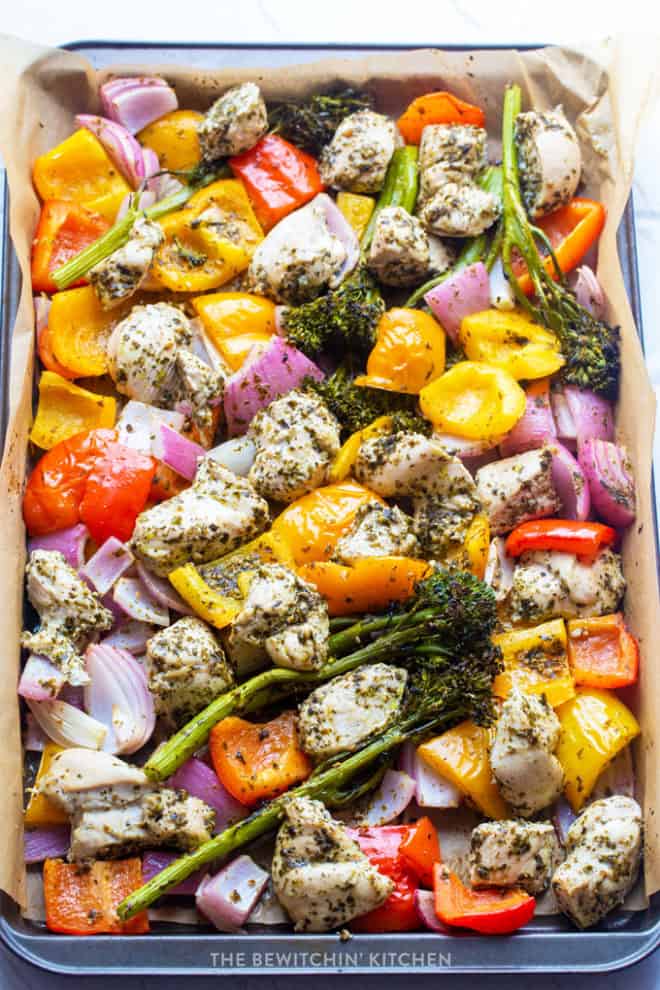 Roasted chicken and vegetables out of the oven on a sheet pan lined with parchment paper