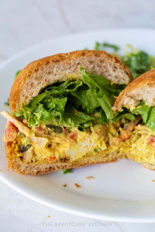 curry chicken sandwich sliced in half on a kaiser bun with lettuce