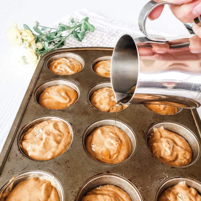 pouring maple syrup onto pumpkin banana muffins batter