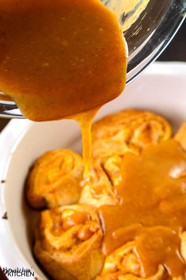 pouring homemade glaze over pumpkin cinnamon rolls