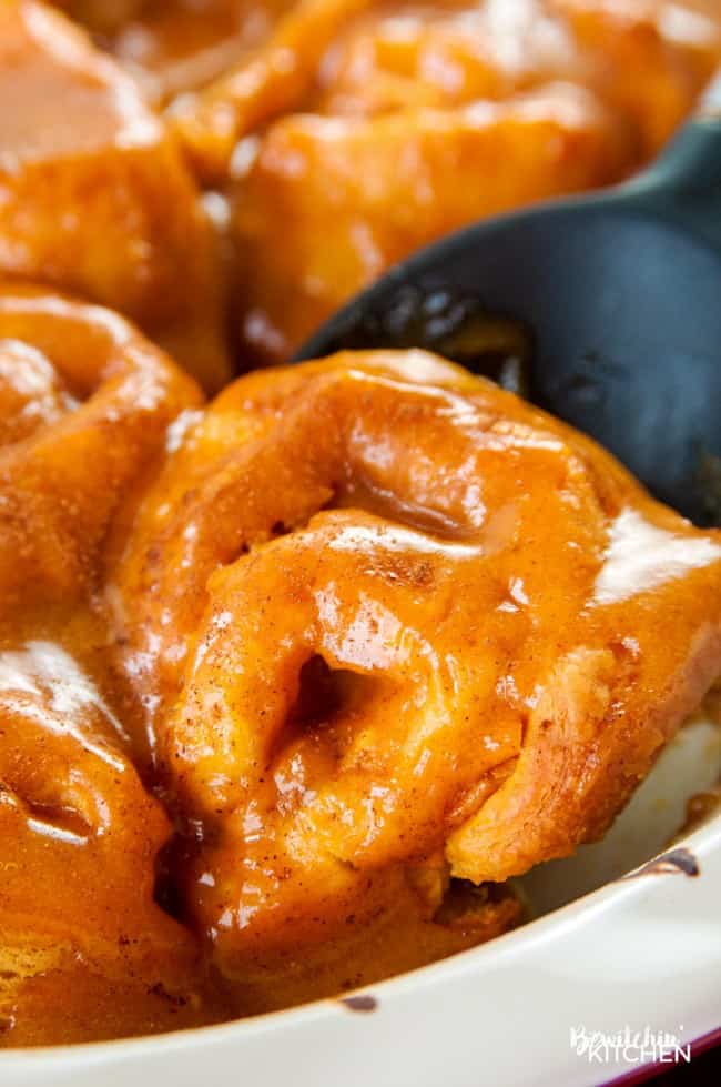 closeup of glazed pumpkin cinnamon rolls in a pie plate