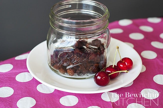 glass jar of dehydrated cherries on a plate on a pink polka dot tablecloth