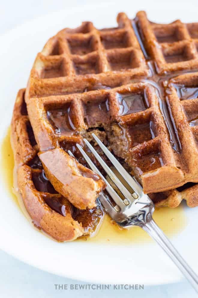 fork cutting into stack of gluten free waffles with syrup