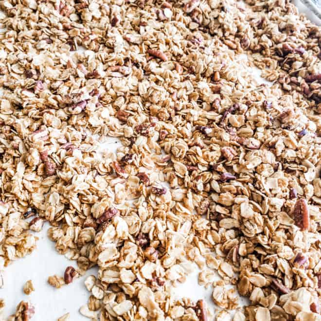 baked maple granola spread out on a baking sheet