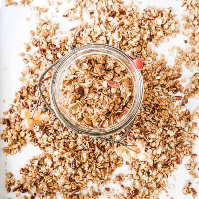 overhead of a glass jar filled and surrounded by pumpkin spice granola