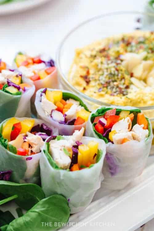 Chicken spring rolls halved on a plate with dipping sauce