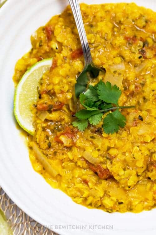 closeup of curry lentil soup with cilantro and lime wedge