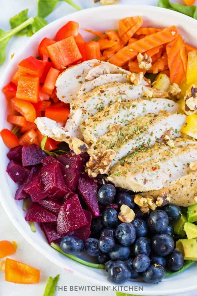 rainbow salad topped with sliced baked chicken breast