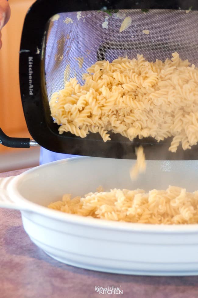 Noodles being dumped into a baking dish to make a spinach pasta bake