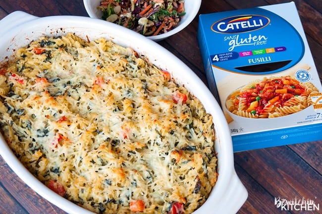 Artichoke casserole in a white baking dish alongside a box of Catelli gluten free Fusilli pasta