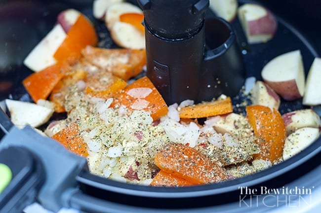 Close up of TFal Actifry air fryer with roasted potatoes and peppers in the pan