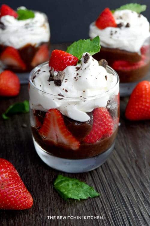 Side view of a chocolate parfait layered with strawberries and whipped cream