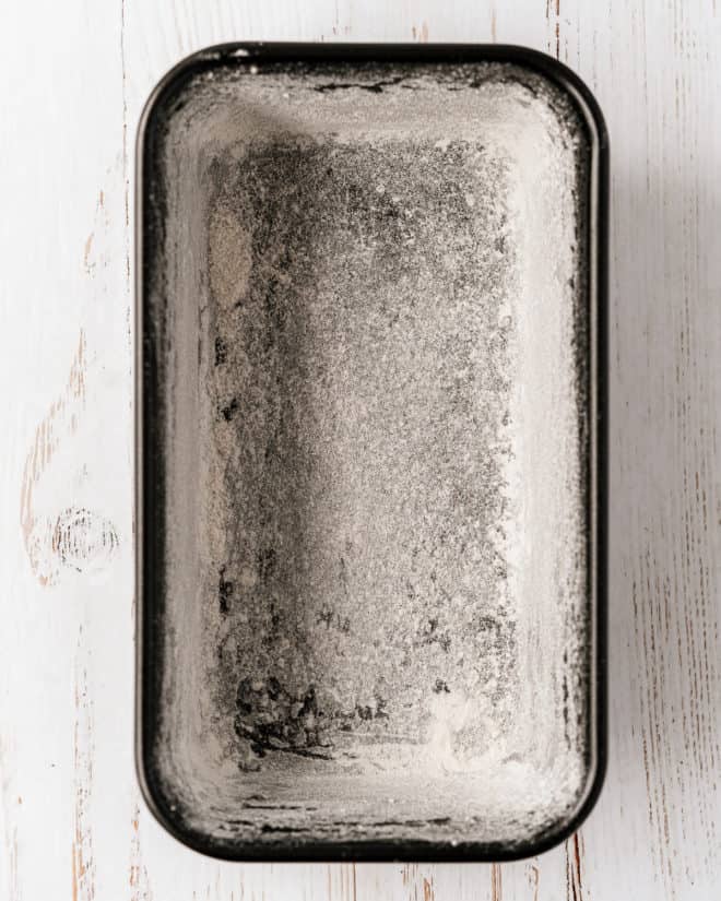 A loaf pan for lemon poppyseed pound cake that has been prepared with oil and flour.