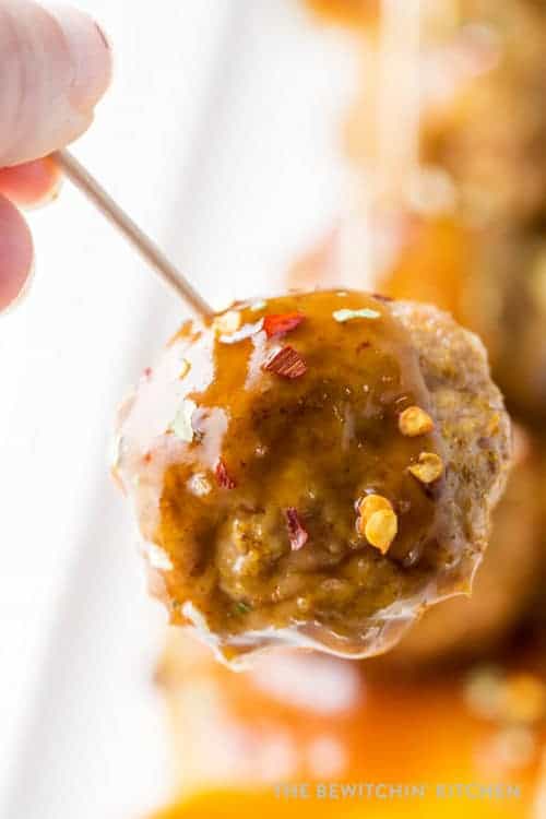 a close up of chicken meatballs with curry on a toothpick