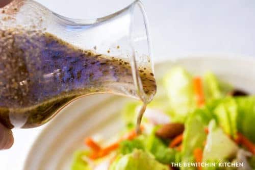 Greek vinaigrette salad dressing being poured over a salad