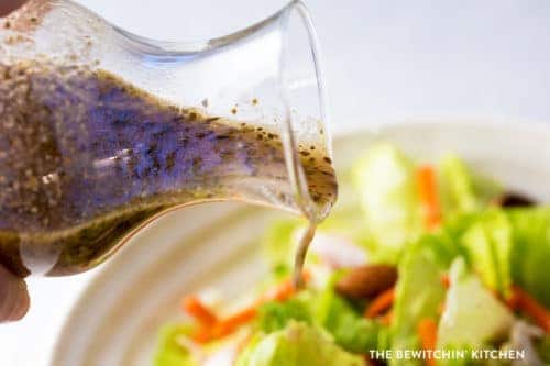 Greek vinaigrette salad dressing being poured over a salad