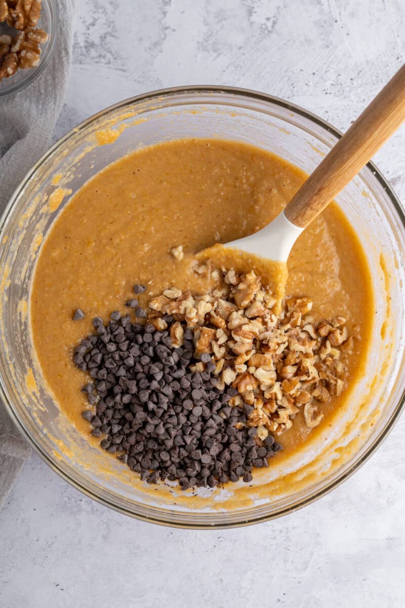 Folding in add-ins to gluten free pumpkin muffins batter in a glass bowl