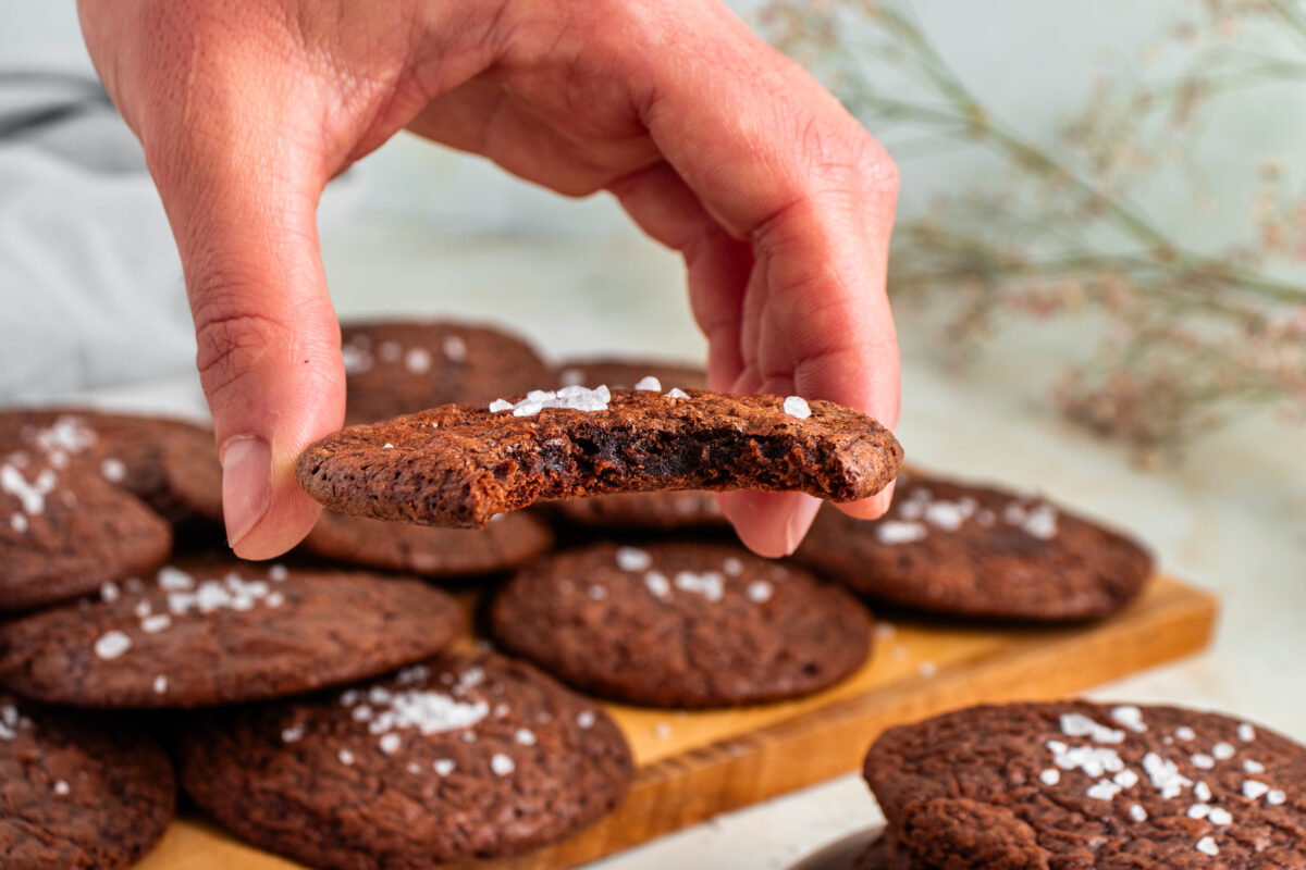 Hand holding a brownie cookie with a bite taken out of it