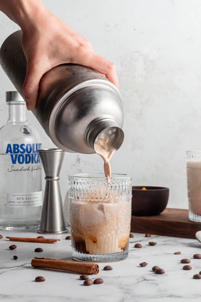 Pouring pumpkin spice white russian into a glass of ice